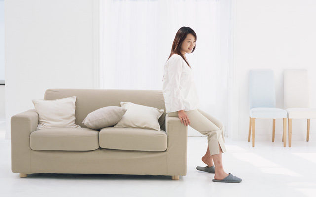 ソファーの肘掛けに腰かける女性